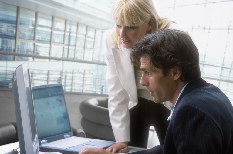Professionals collaborating around laptops in an office